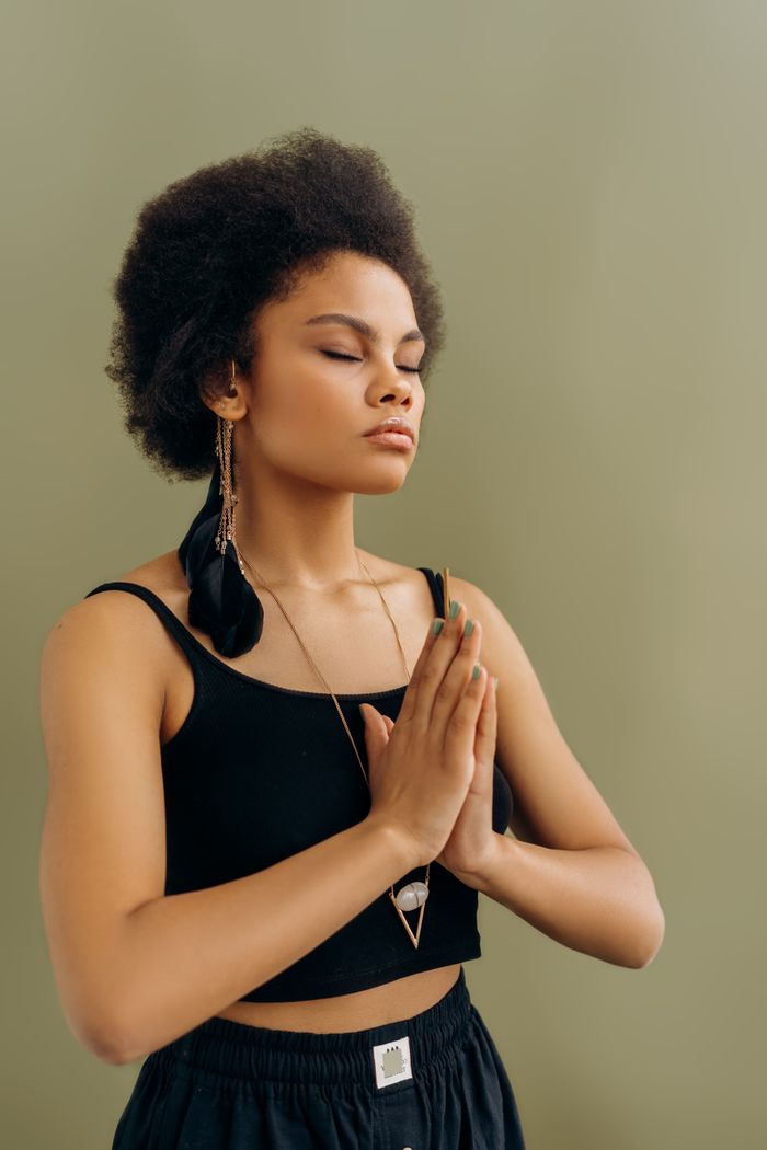 The Art of Drawing Readers In: Your attractive post title goes here Serene African American woman practicing meditation with hands in prayer pose.